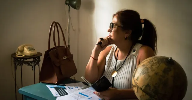 Une femme pensive à un bureau avec un globe, un passeport et des documents