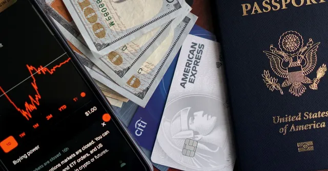 Passeport américain, billets en dollars et cartes bancaires posés sur une table